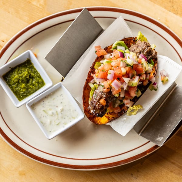 Savory beef taco with fresh salsa and two dipping sauces on a plate.