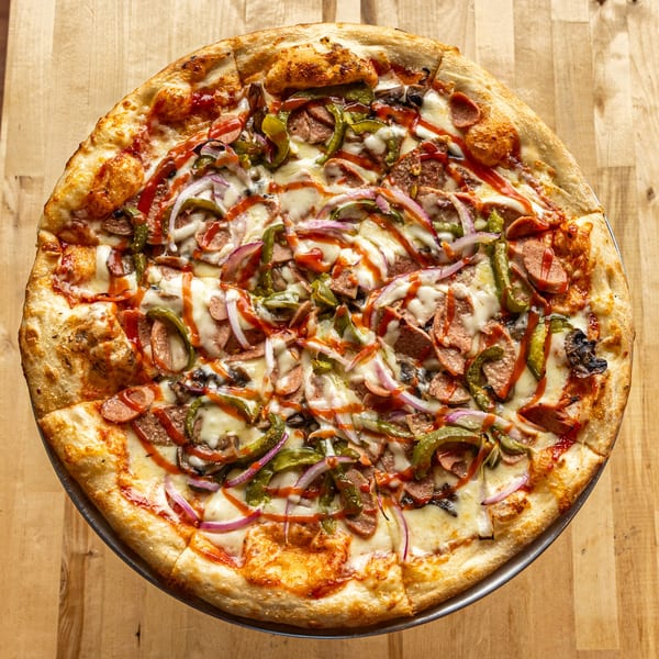 Italiamo Kitchen pizza with sausage, green peppers, red onions, mushrooms, and a BBQ sauce drizzle.