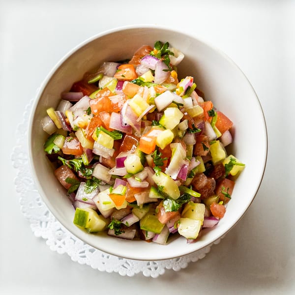 Close-up of a fresh Italiamo Kitchen salad with diced tomatoes, cucumbers, and red onions.